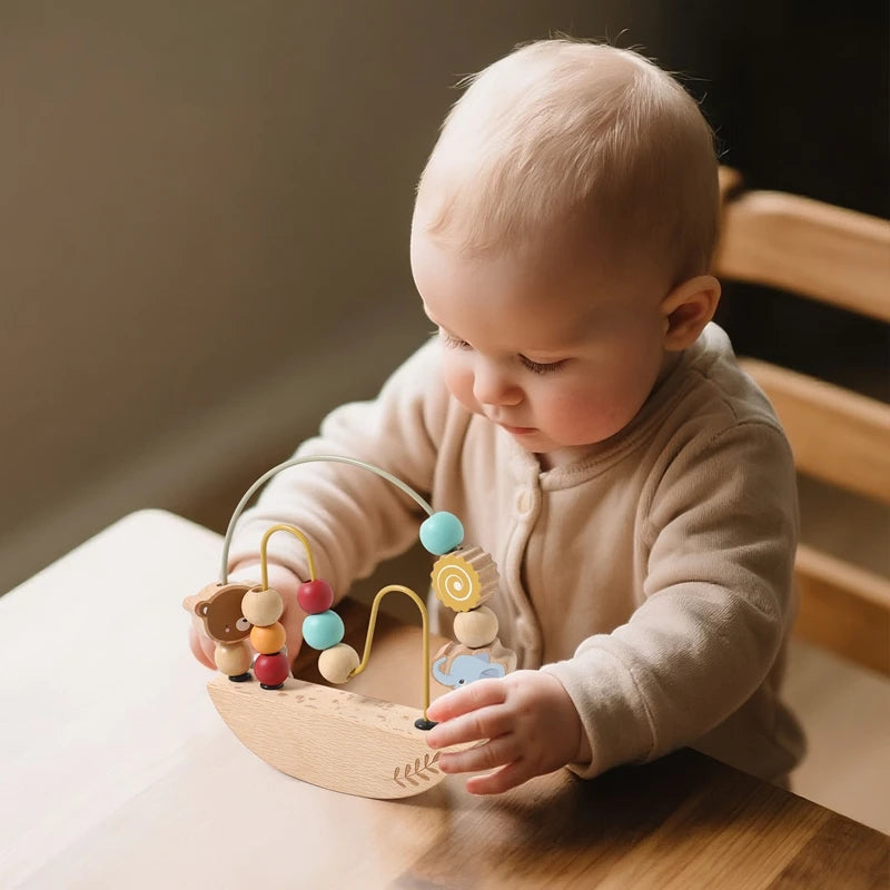 Baby playing with a wooden bead maze toy on a wooden table.