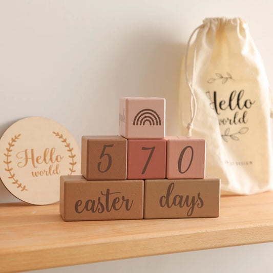 Stack of wooden blocks with numbers and text on a shelf, with a 'Hello world' bag in the background.